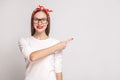 look at this side. pointing finger. portrait of beautiful emotional young woman in white t-shirt with freckles, glasses, red lips Royalty Free Stock Photo