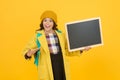 Look there. Happy girl point to blackboard yellow background. Small kid with blank blackboard. Little child hold school