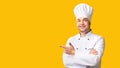 Male Chef Pointing Fingers Aside Standing On Yellow Background, Panorama