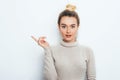 Look There! Surprised Attractive young female lady wearing in sweater with hair bun showing emotions on white wall. Shocked woman Royalty Free Stock Photo