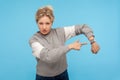 Look at time! Displeased impatient woman with curly hair in sweatshirt pointing at wrist watch, anxious about delay Royalty Free Stock Photo