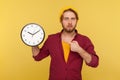 Look at time! Portrait of impatient hipster bearded guy in checkered shirt pointing big clock and looking worried Royalty Free Stock Photo