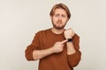 Look at time! Portrait of worried impatient man with beard in sweatshirt pointing wrist watch and looking anxious Royalty Free Stock Photo