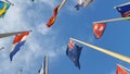 Look up view to the row of flags attached to the poles, over blue sky background Royalty Free Stock Photo