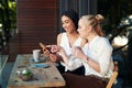 Look who just likes our picture. two young women looking at something on a cellphone while sitting at a cafe. Royalty Free Stock Photo