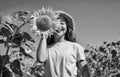 Look at it. yellow flower of sunflower. happy childhood. beautiful girl wear straw summer hat in field. pretty kid with Royalty Free Stock Photo