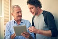 Look youngster, let me show you how its done. a man showing his elderly father how to use a tablet at home.