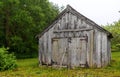 Looking across the green grass at an old black wooden barn building with closed doors Royalty Free Stock Photo