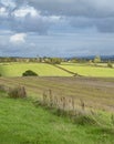 Looking across typical rolling English Cotswold landscape towards a church in the middle distance Royalty Free Stock Photo