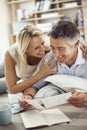 Looking back on fond memories. an affectionate mature couple lying on their living room floor looking at photographs. Royalty Free Stock Photo