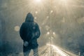 Looking at the back of a hooded figure looking out on a motorway and traffic trails on a moody foggy winters night. With light fla Royalty Free Stock Photo