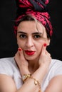 Looking at the camera woman in a silk scarf, white t-shirt on a black background. Royalty Free Stock Photo