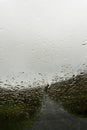 Looking through a car window blurred by raindrops. As a road crosses a bleak moorland valley. On a moody, misty day. Wales, UK