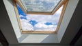 Looking on clouds flying past at the blue sky through open attic window in house roof Royalty Free Stock Photo