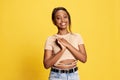 Looking delightful. Portrait of beautiful young african girl in casual clothes posing with smile against yellow studio