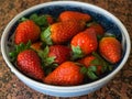 Looking down from above onto a bowlful of fresh strawberries on a table