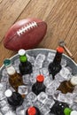 Looking down on an American football with a tub of assorted ice cold beer bottles on a wooden table Royalty Free Stock Photo