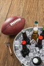 Looking down on an American football with a tub of assorted ice cold beer bottles on a wooden table Royalty Free Stock Photo