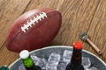 Looking down on an American football with a tub of assorted ice cold beer bottles on a wooden table Royalty Free Stock Photo