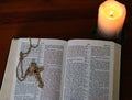 Candle glowing near gold cross on open Bible Royalty Free Stock Photo