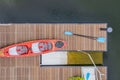 Looking down on a dock in the water with a kayack and paddles and life vests beside a kayac lanching platform