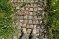 Looking down on feet in shoes standing on cobblestone path