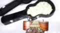 Looking down guitar neck, in focus, case with money in distance, extreme depth of field