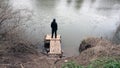 Looking down on a hooded figure standing on a fishing platform, looking out across a river Royalty Free Stock Photo