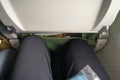 Looking down narrow legroom space in commercial airplane, another passenger leg close