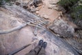 Looking down an old wooden ladder leaning against a rocky cliff, first person perspective. Royalty Free Stock Photo