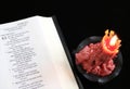 Opened Bible with burning rose colored candle Royalty Free Stock Photo