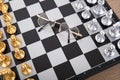 Looking down and shooting the facing chess pieces on the chessboard and a pair of glasses between the two sides Royalty Free Stock Photo
