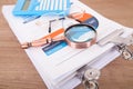 Looking down and shooting a stack of business-related documents on the table and the magnifying glass and calculator on the docume