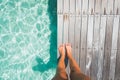 Tanned feet of a woman standing on a wooden deck by tropical ocean Royalty Free Stock Photo