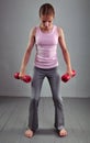 Looking down teenage sportive girl is doing exercises to develop muscles isolated on grey background. Sport healthy lifestyle