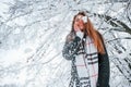 Looking down and throwing the snow. Beautiful young woman is outdoors in the winter forest Royalty Free Stock Photo