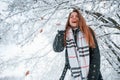 Looking down and throwing the snow. Beautiful young woman is outdoors in the winter forest Royalty Free Stock Photo