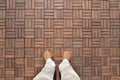 Top wide angle view on two feet in shoes standing on wooden floor. Brown checkers pattern. Royalty Free Stock Photo