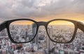 Looking through eyeglasses to city sunset view, focused on lens with blurry background Royalty Free Stock Photo