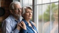 Elderly spouses hug look at window meet twilight years together Royalty Free Stock Photo