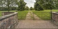 Looking at a gateway with metal gates down a pathway in a field Royalty Free Stock Photo