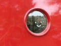 Looking hole: smile on a round window in a red frontdoor