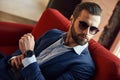 Looking just perfect...Young and bearded businessman in sunglasses is looking away while sitting on office sofa Royalty Free Stock Photo