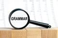 Looking through a magnifying glass at the word GRAMMAR, a business concept. Magnifying glass on the background of columns of Royalty Free Stock Photo