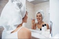 Looking into the mirror. In the bathroom. Woman in white towel in head have care of herself Royalty Free Stock Photo