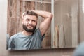 Bearded dark-haired mature man looking into mirror