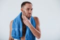 Looking in the mirror. Man with blue towel stands against white background in the studio Royalty Free Stock Photo