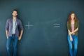 Looking for that missing connection. a young couple standing in front of a blackboard with symbols written on it. Royalty Free Stock Photo