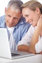 Looking at old photos on the laptop. A mature couple looking content as they work on their laptop at home. Royalty Free Stock Photo