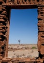 Looking at an old windmill through a ruined window frame Royalty Free Stock Photo